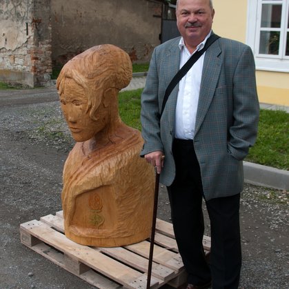 Pan Oldřich Polášek se sochou dívky, kterou vyřezal z lánské lípy. Jméno dívky vyberou děti z Lán (autor fotografie Petr Vícha).